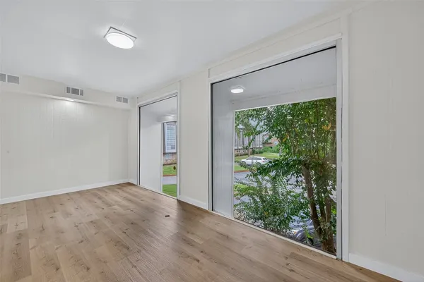 a view of empty room with wooden floor and fan