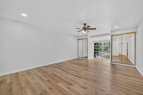 a view of an empty room with a window and wooden floor