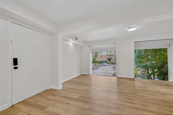 a view of an empty room with a window and wooden floor