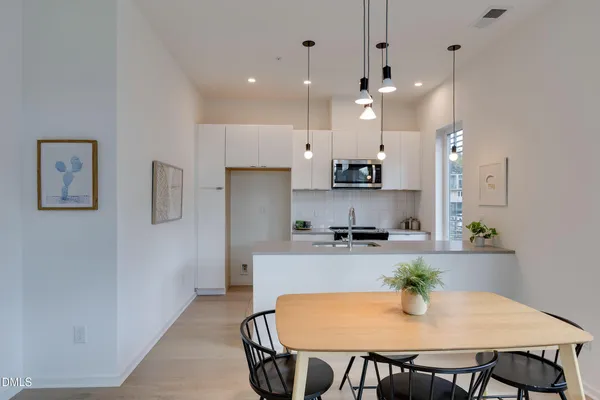 a kitchen with stainless steel appliances a dining table chairs and refrigerator
