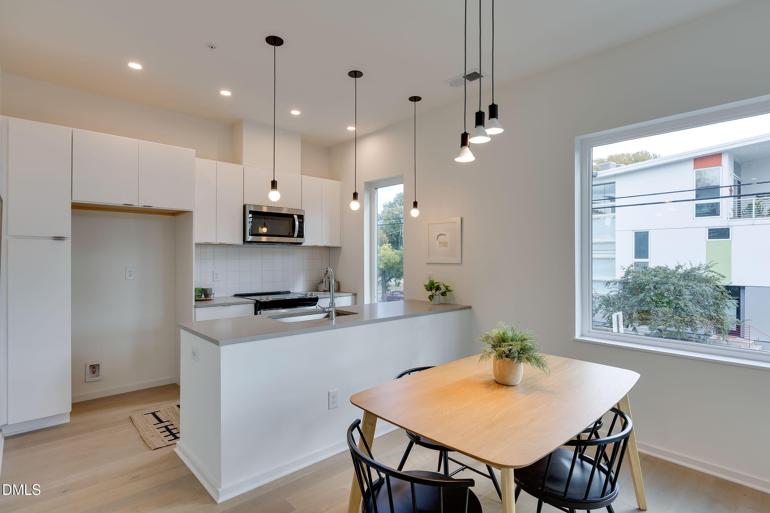 521 North Mangum Street, Unit 21 Durham, NC 27701 - Photo 6 of 21 a kitchen with kitchen island a stove a refrigerator a sink a dining table and chairs with wooden floor