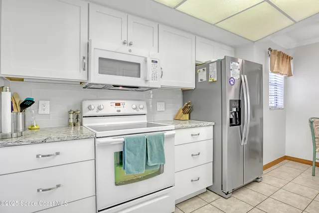 a kitchen with white cabinets and refrigerator