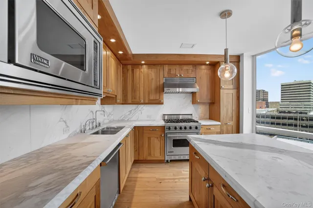 a kitchen with stainless steel appliances granite countertop a sink a stove and a wooden floors