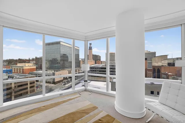 a living room with furniture a large window and wooden floor