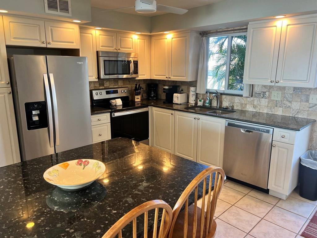 6006 Midnight Pass Road, Unit 40 Sarasota, FL 34242 - Photo 6 of 25 a kitchen with stainless steel appliances granite countertop a sink a stove a microwave a refrigerator and island