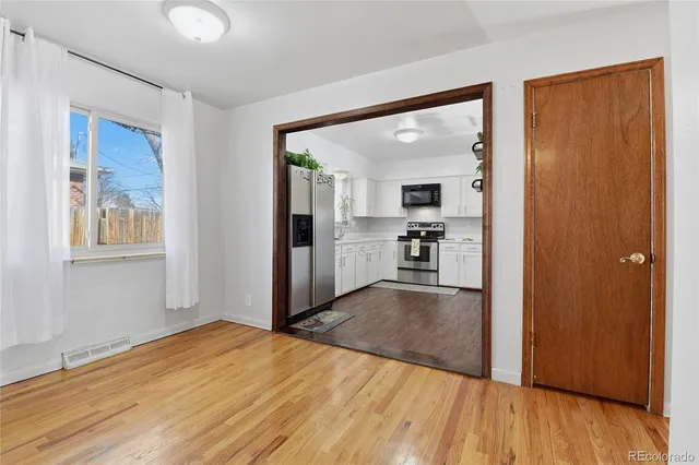 a view of a living room with wooden floor and a kitchen