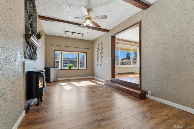 an empty room with windows fireplace and wooden floor