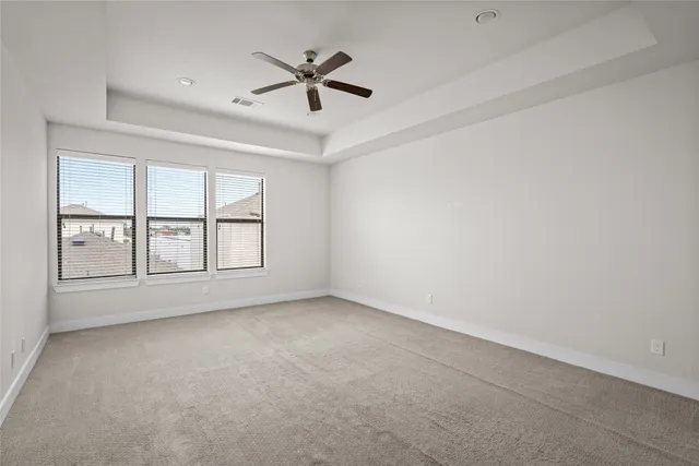 an empty room with chandelier fan and windows