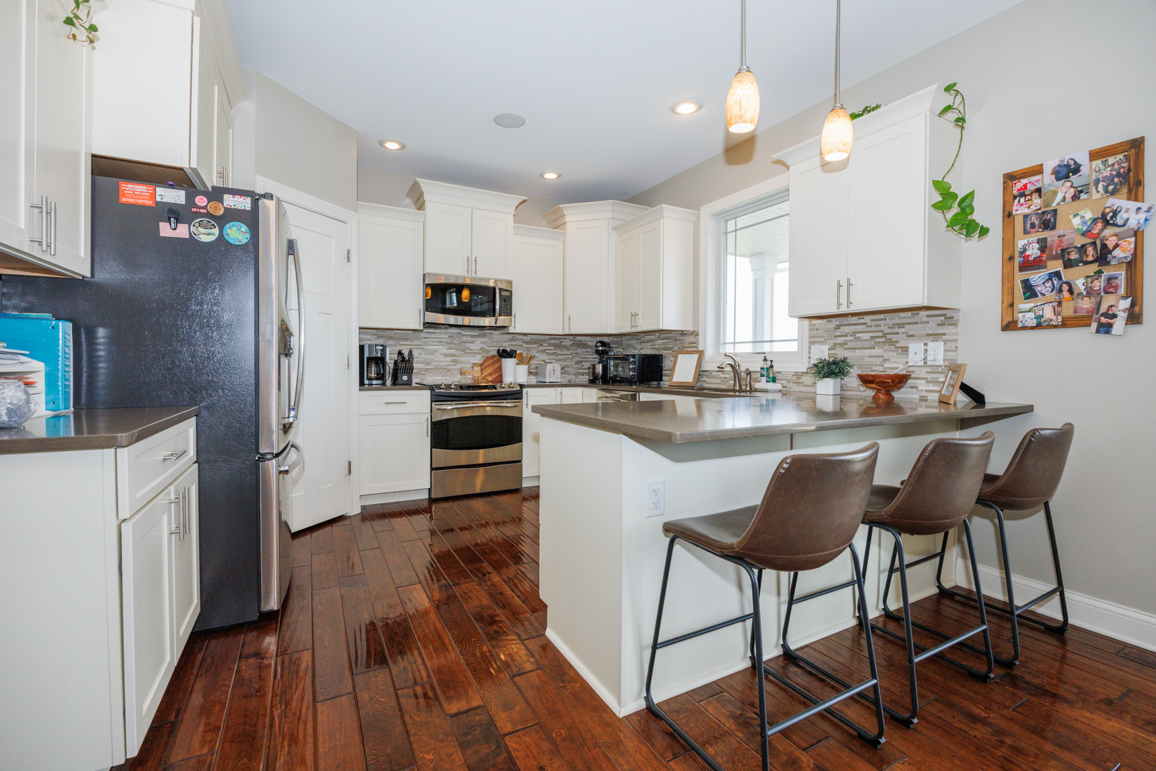 114 Mallard Way Hudson, IL 61748 - Photo 13 of 65 a kitchen with stainless steel appliances a stove a sink dishwasher a refrigerator and a dining table with wooden floor