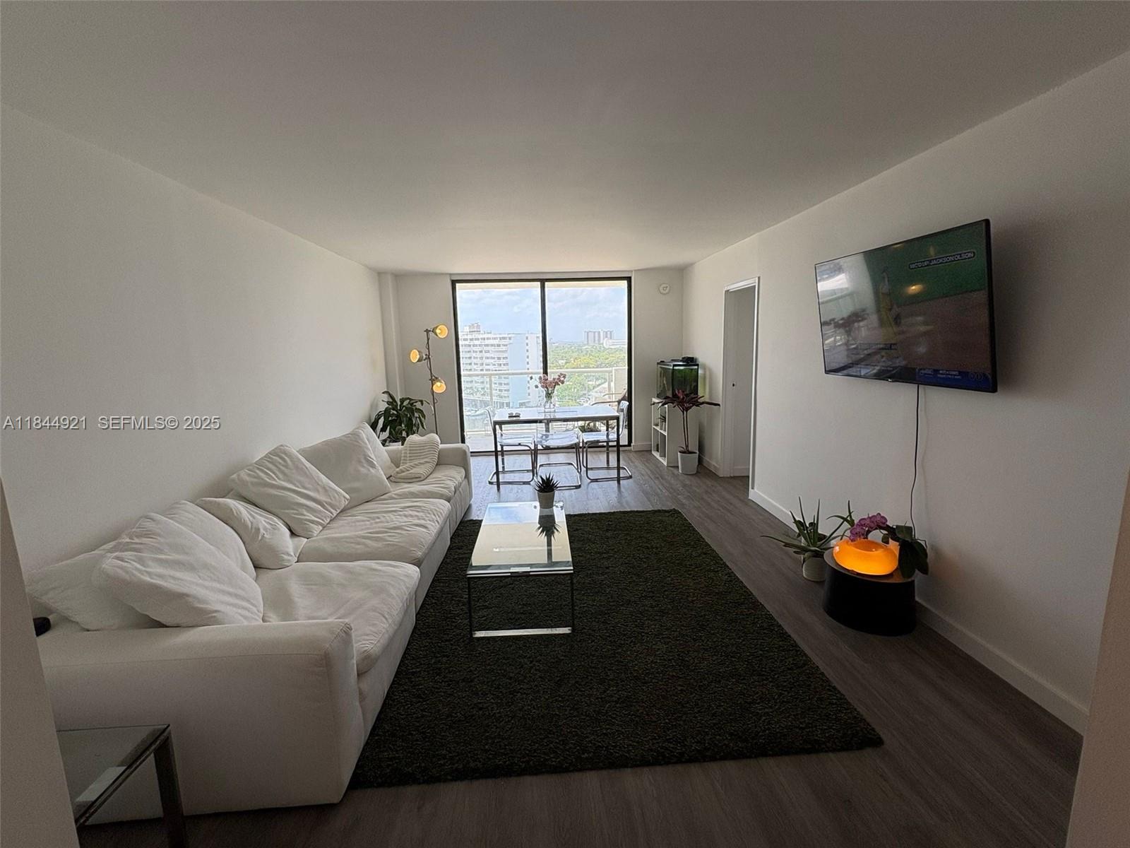 13499 Biscayne Boulevard, Unit 902 North Miami, FL 33181 - Photo 11 of 15 a living room with furniture and a flat screen tv