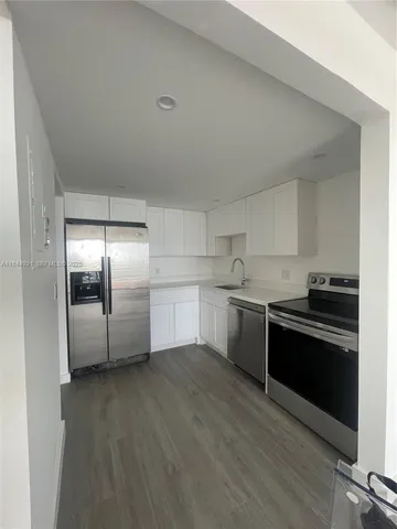 a kitchen with granite countertop a refrigerator and a stove top oven