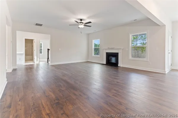 a view of a livingroom with wooden floor a fireplace and windows