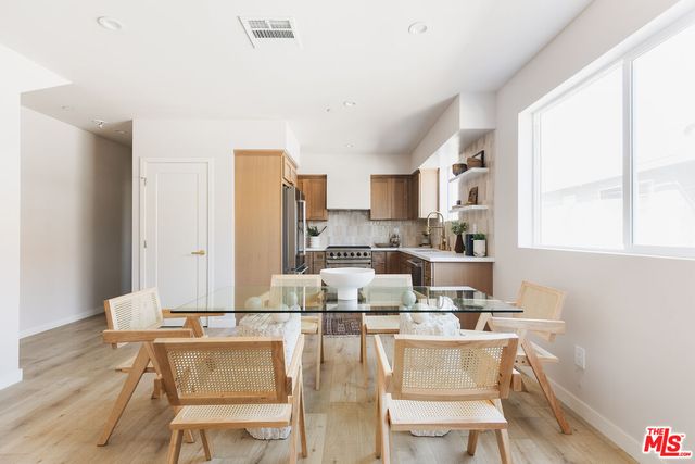 a dining room with stainless steel appliances kitchen island granite countertop a table chairs and a refrigerator