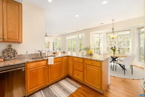 a dining room with wooden floor a chandelier a glass table and chairs
