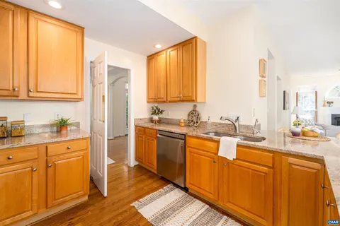 a kitchen with stainless steel appliances granite countertop a refrigerator a sink dishwasher and wooden cabinets with wooden floor