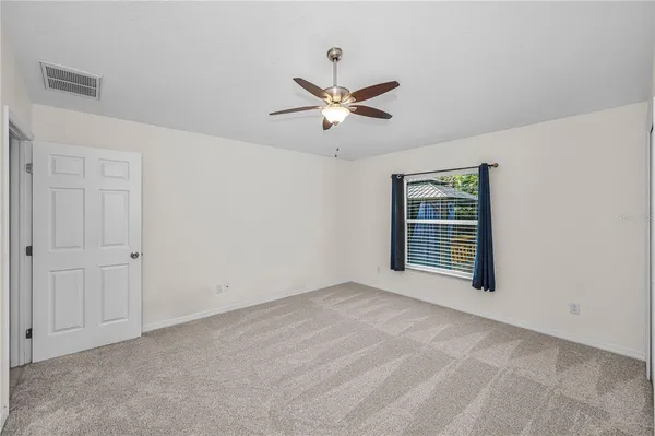 an empty room with a chandelier fan and windows