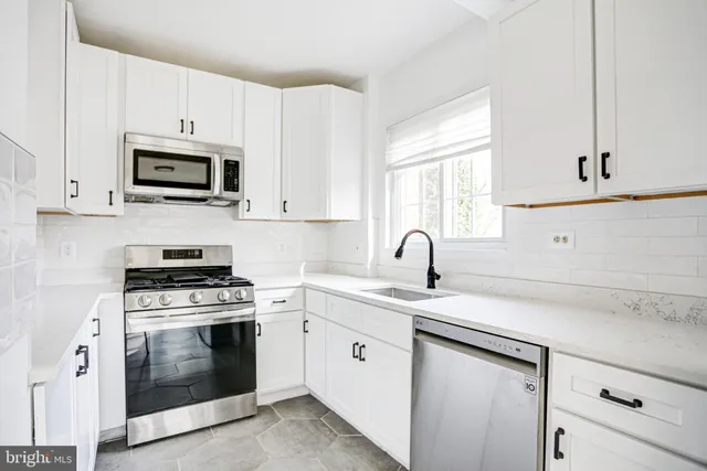 a kitchen with white cabinets and refrigerator