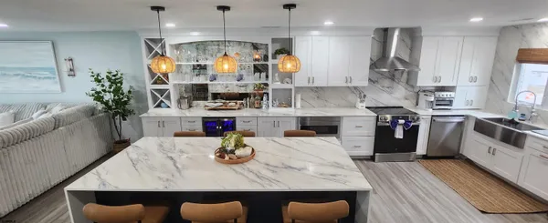 a kitchen with stainless steel appliances granite countertop a sink dishwasher and a dining table with wooden floor