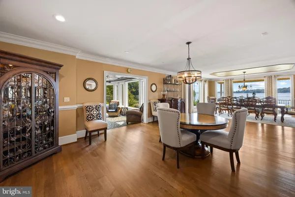 a dining room with wooden floor a chandelier a glass table and chairs