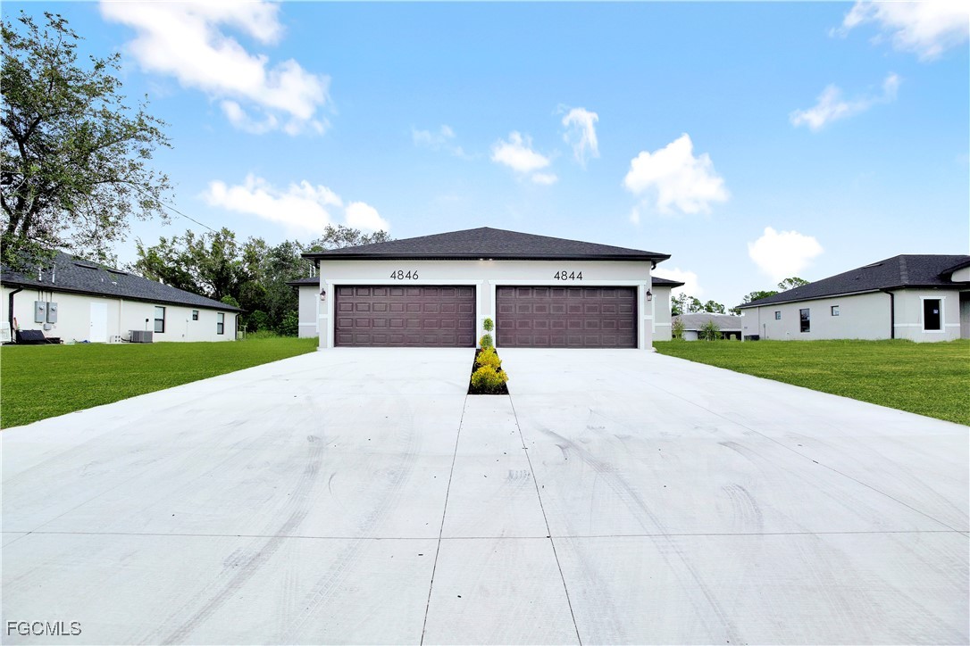 a view of a house with a yard and large tree