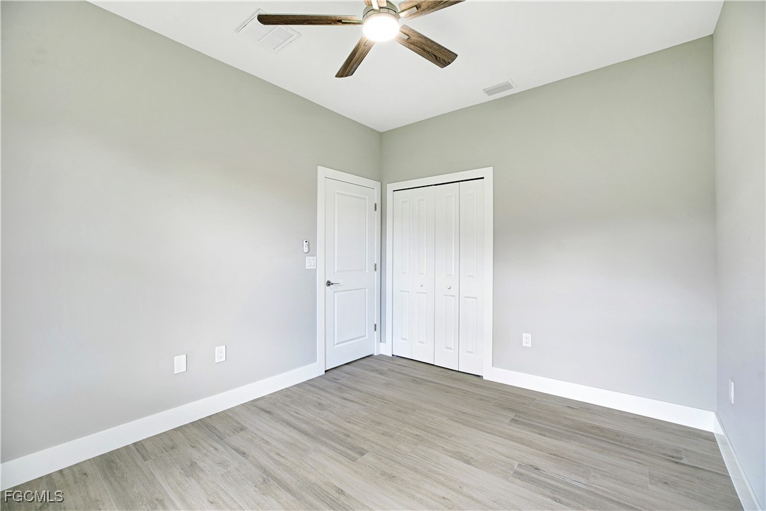 4846 30th Street Southwest Lehigh Acres, FL 33973 - Photo 11 of 14 an empty room with wooden floor and ceiling fan