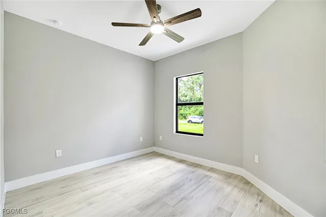 an empty room with a window and a ceiling fan
