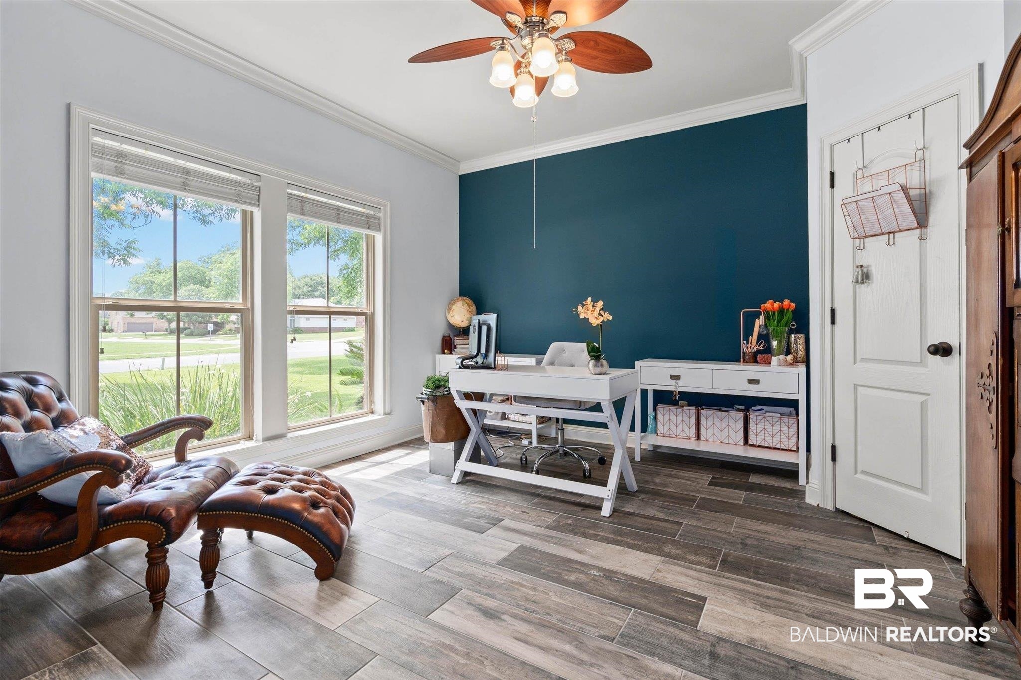24908 Bosbyshell Avenue Daphne, AL 36526 - Photo 22 of 49 Interior room featuring wood-finish flooring, two large windows, a decorative ceiling fan, crown molding, and a contrasting accent wall