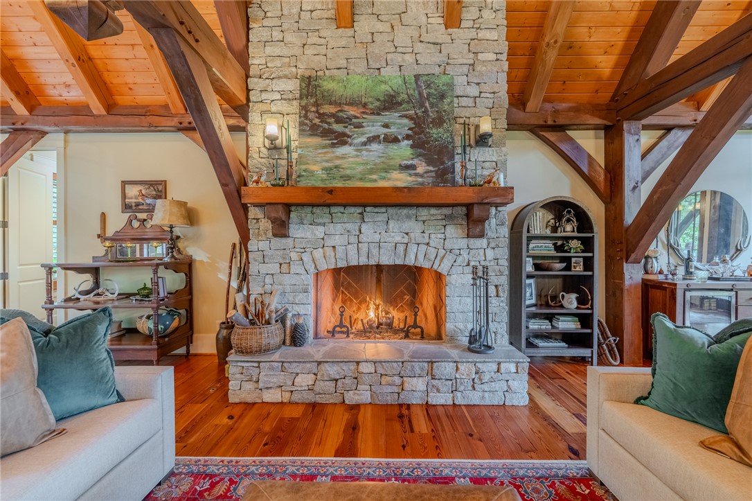 102 State Rd S-39-143 Sunset, SC 29685 - Photo 11 of 47 This inviting living space showcases a beautiful stone fireplace with exposed beam ceilings and hardwood floors.