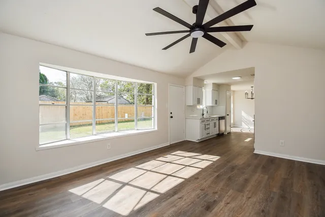 a view of an empty room with window and wooden floor