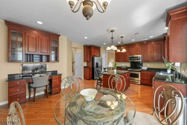 a kitchen with stainless steel appliances granite countertop a stove top oven a sink a dining table and chairs with wooden floor