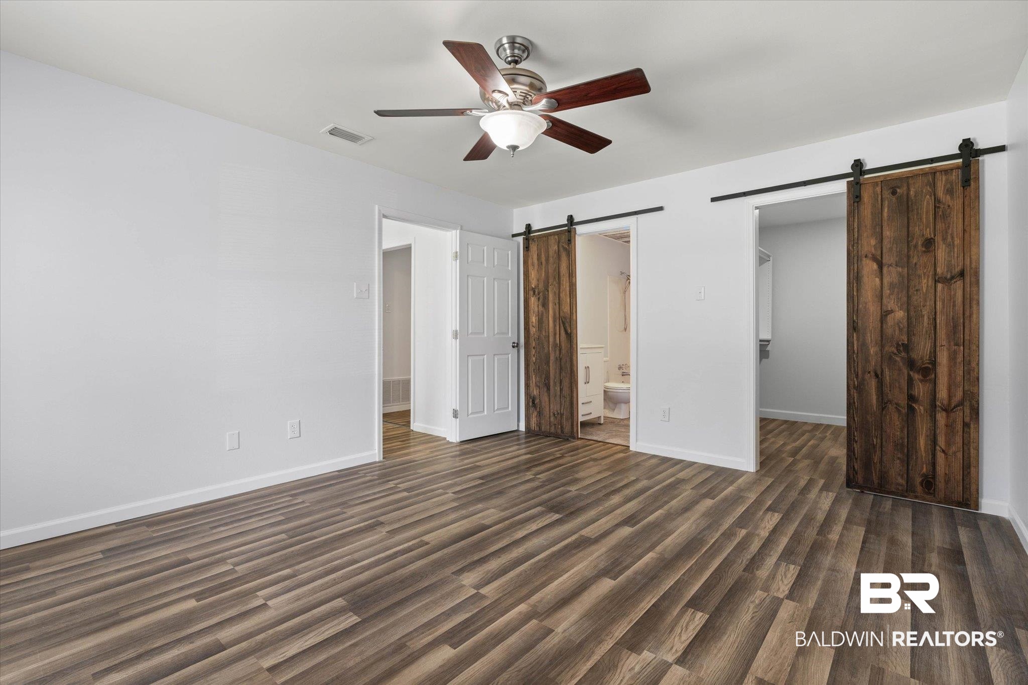 123 Richmond Road Daphne, AL 36526 - Photo 12 of 35 Unfurnished bedroom with a barn door, a spacious closet, dark wood-style flooring, and ensuite bath