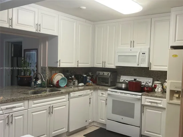 a kitchen with white cabinets and white appliances