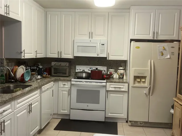 a kitchen with stainless steel appliances kitchen island granite countertop a refrigerator and cabinets