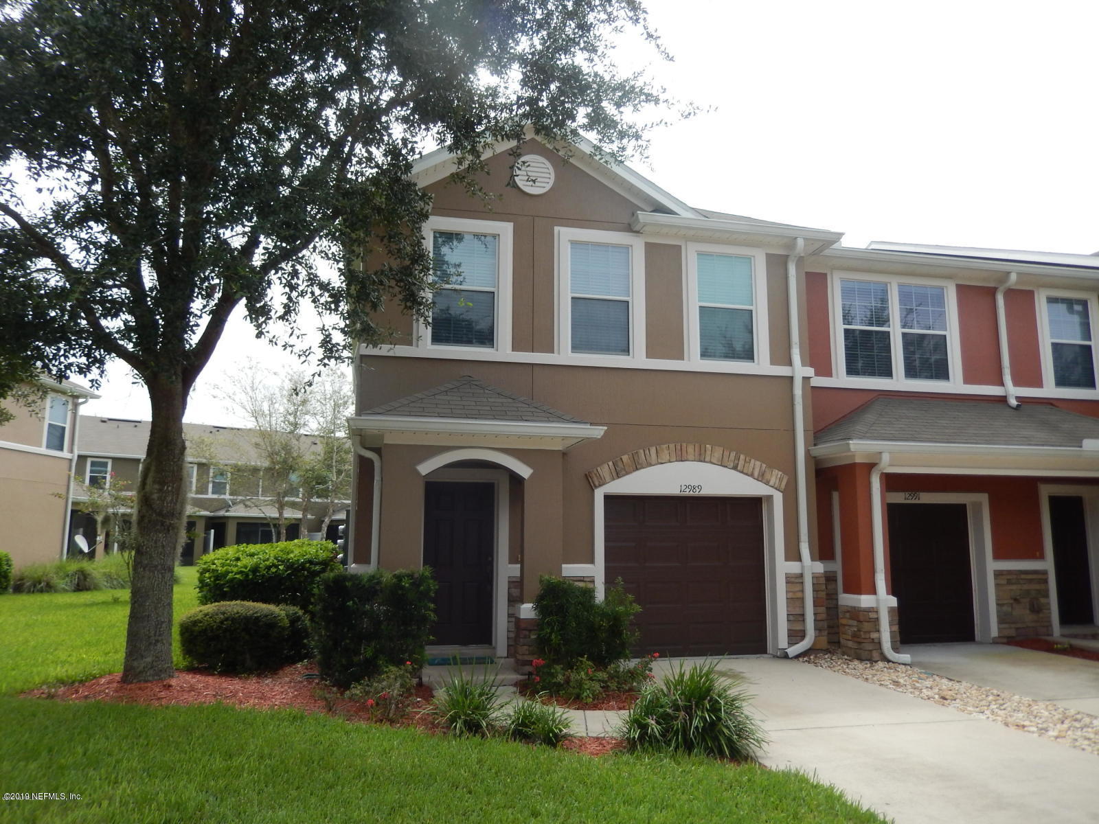 a front view of a house with garden and garage