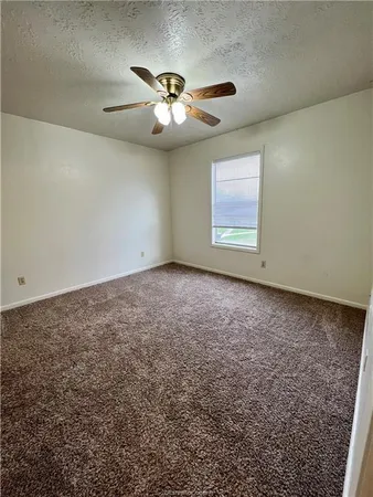 an empty room with windows and chandelier fan