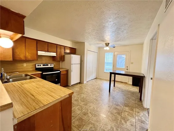 a kitchen with stainless steel appliances kitchen island granite countertop a refrigerator a stove and a sink with granite countertops