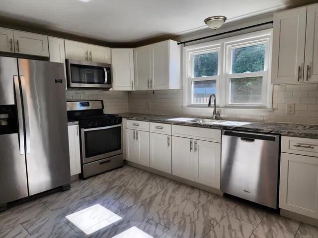 a kitchen with granite countertop white cabinets and white appliances