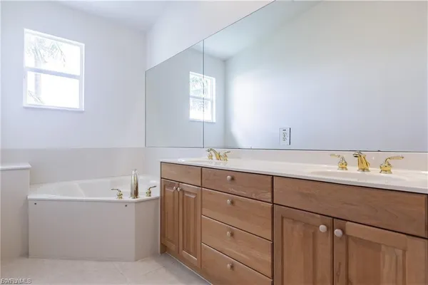 a bathroom with a sink double vanity granite tub and a window