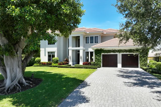 a front view of a house with a yard and trees