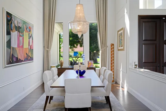 a dining room with furniture a painting a chandelier and wooden floor