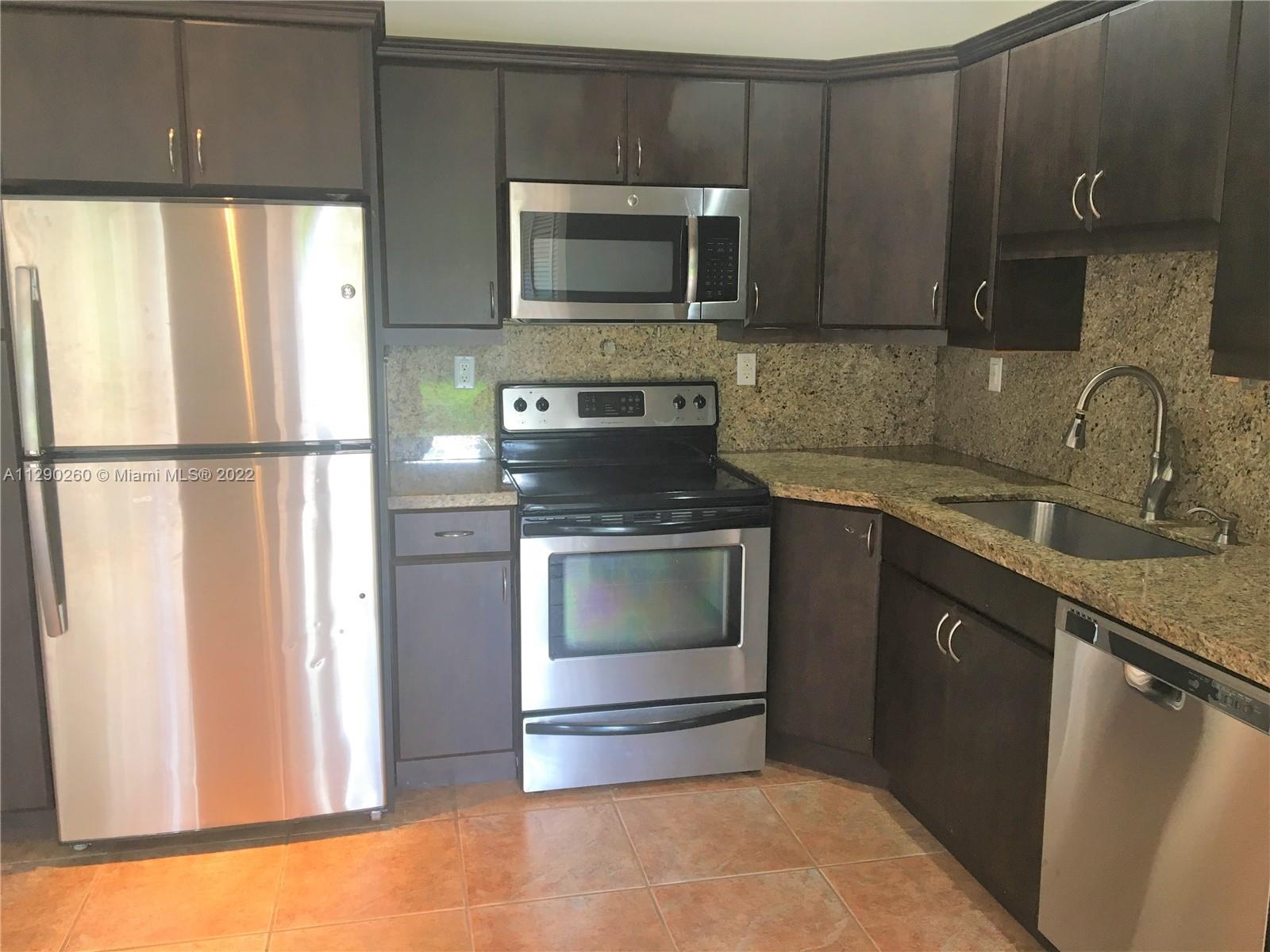 6442 Southwest 37th Street Miami, FL 33155 - Photo 3 of 14 a kitchen with granite countertop a refrigerator stove and microwave