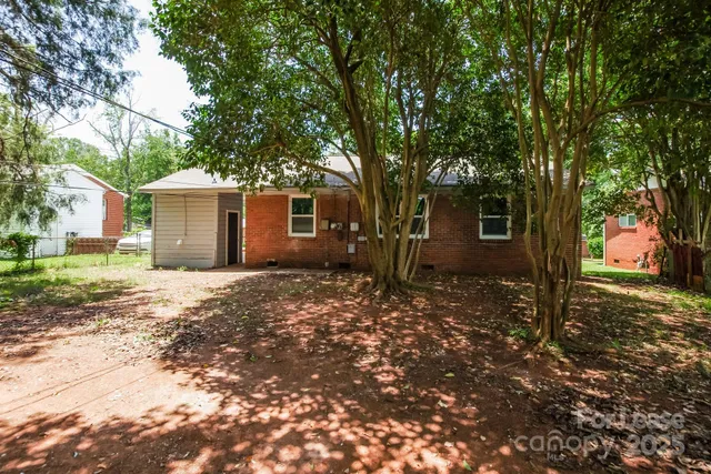 a backyard of a house with large trees and outdoor shower