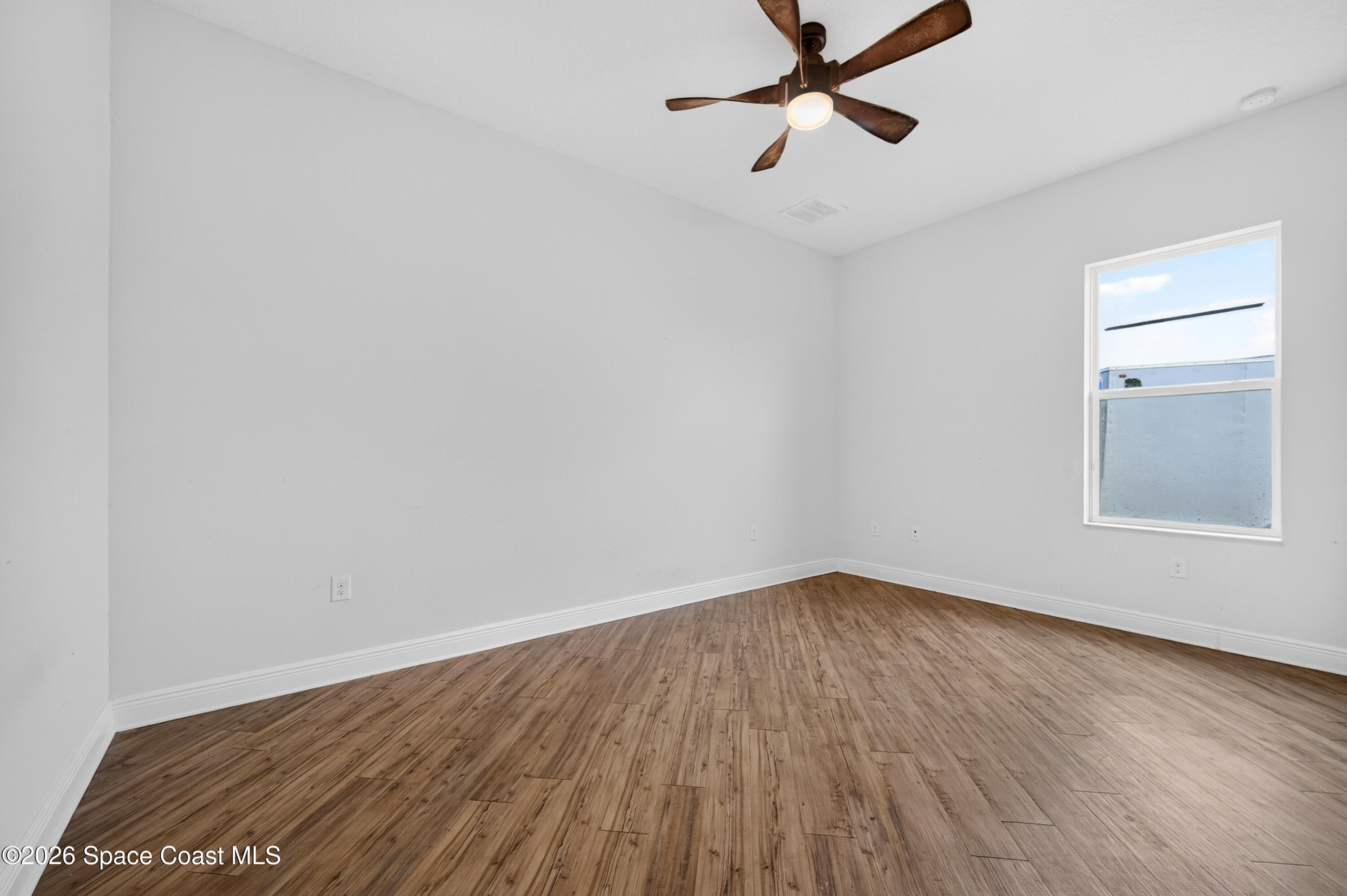 1475 Dalbora Road Merritt Island, FL 32953 - Photo 45 of 57 an empty room with wooden floor ceiling fan and windows