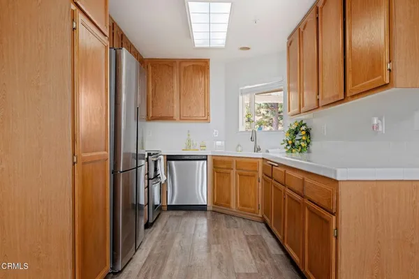 a kitchen with stainless steel appliances granite countertop a refrigerator a sink dishwasher and wooden cabinets with wooden floor