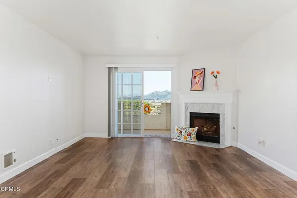 a view of an empty room with wooden floor fireplace and a window