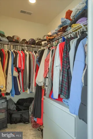 a view of walk in closet with clothes and shoes