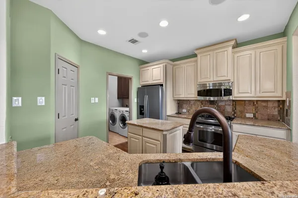 a kitchen with stainless steel appliances kitchen island granite countertop a sink and cabinets