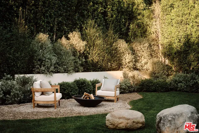 a view of a backyard with couches table and chairs and garden