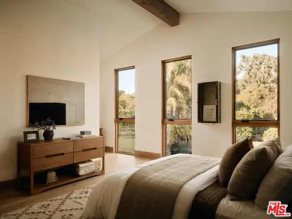a bedroom with a balcony a bed and a large window