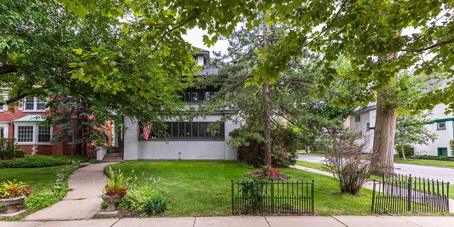 a front view of a house with a yard and tree